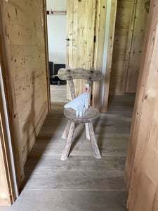 Gruselige Pupe mit Schnabel auf Holzstuhl