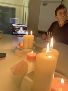 Blick auf leuchtende Kerzen auf dem Tisch. Ein Laptop steht aufgeklappt dabei.