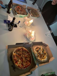 Vier leckere Pizzen auf Tisch, in der Mitte leuchtende Kerzen.