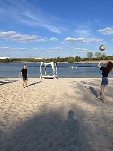 2 Personen spielen Volleyball im Sand.