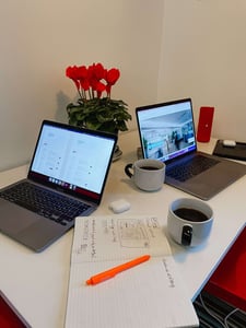 Laptops, Tassen, Notizbuch und Blümchen auf Tisch