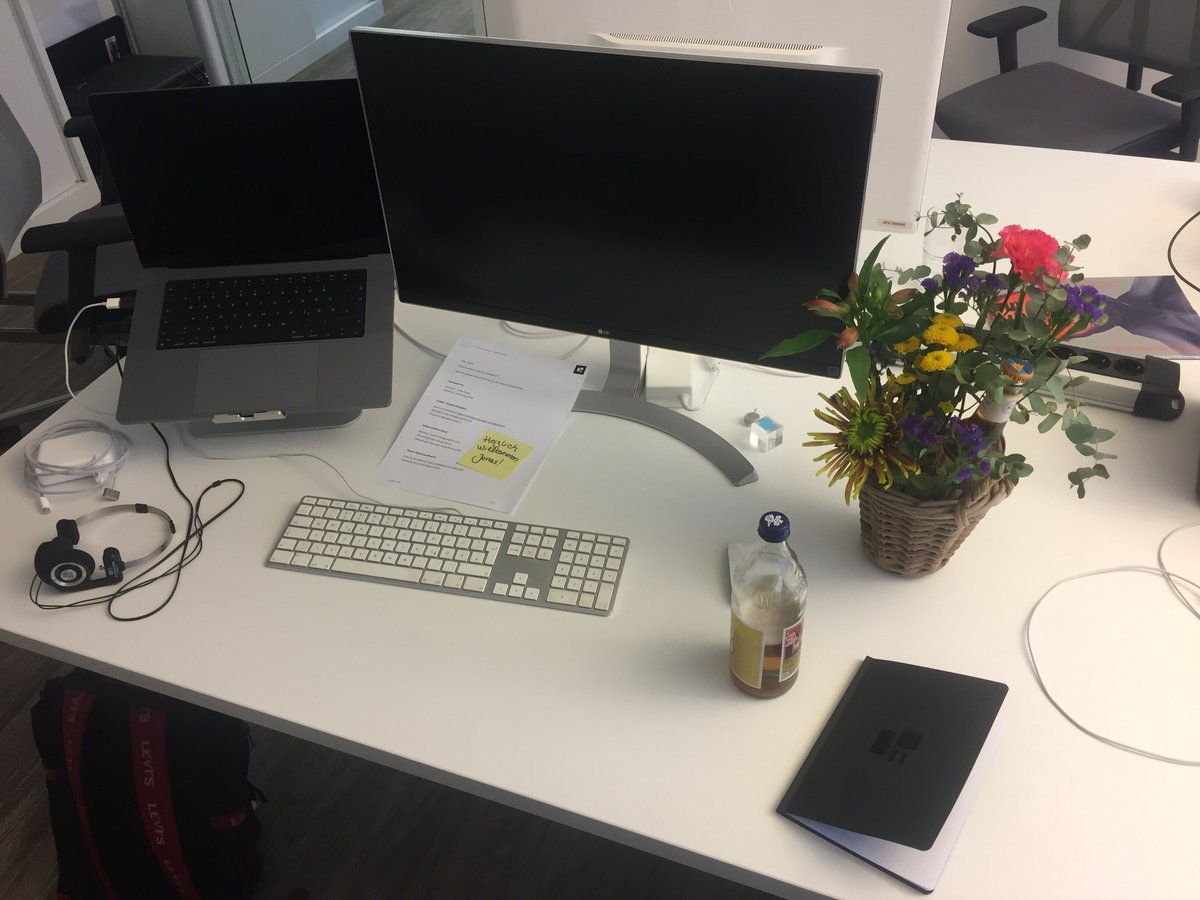 Schreibtisch mit Lapop, zweitem Bildschirm, Notiz, Heft und Blume