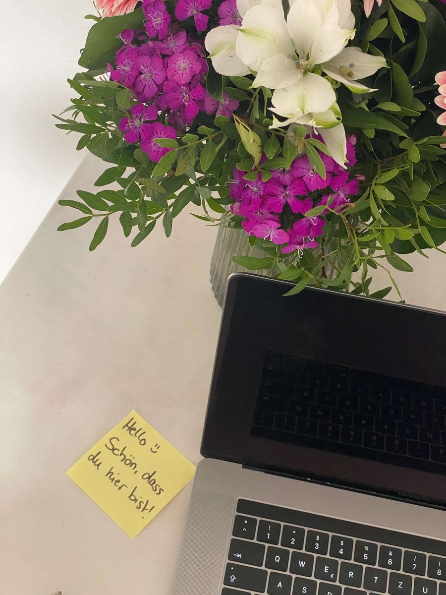Tisch mit Willkommensnotiz, Laptop und Blumenstrauß