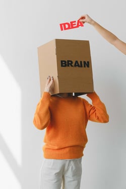 Eine schriftliche „Idee“ wird in das „Gehirn", das aus einem Karton besteht, gesteckt.